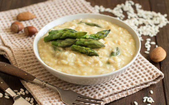 Um prato de risoto cremoso e reconfortante, salpicado com queijo parmesão ralado e adornado com aspargos frescos, uma explosão de sabores em um encontro perfeito de texturas