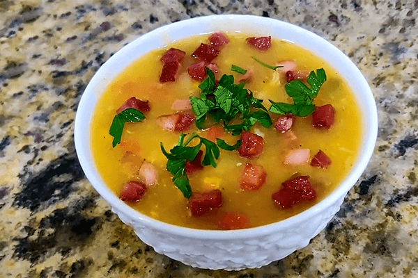 Uma deliciosa tigela de caldo de mandioca fumegante, com queijo parmesão ralado por cima.